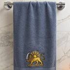A blue-gray hand towel with a gold embroidered lion-sun logo